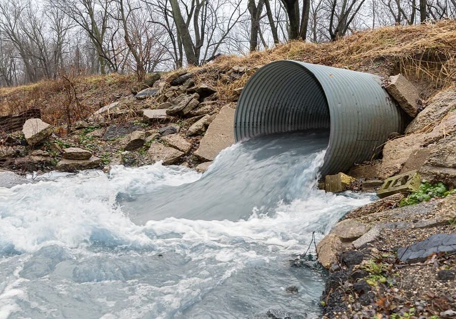 A stream of water flowing from a metal pipe.