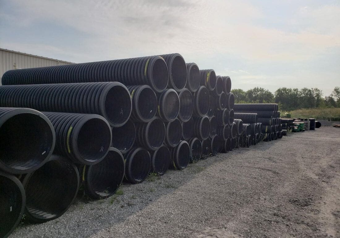 Stacked black corrugated plastic pipes.