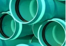 Here's an alt tag for the image: Stack of teal plastic pipes.