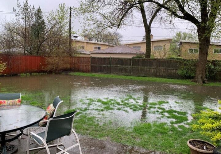 A lawn chair sitting in the middle of a flooded yard.