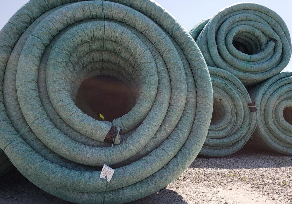 Rolled-up green drainage pipes outdoors.